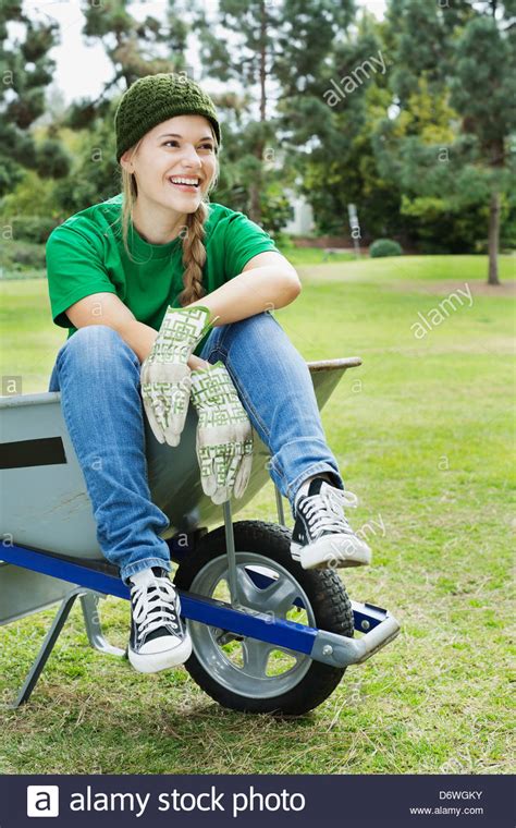 Full Length Of Beautiful Young Environmentalist Sitting In Wheelbarrow