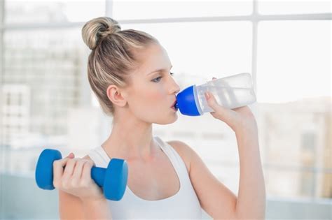 Premium Photo Peaceful Sporty Blonde Drinking Water While Lifting