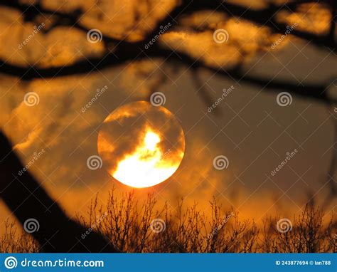 The Evening Sun Setting Through Clouds And Branches Stock Photo Image