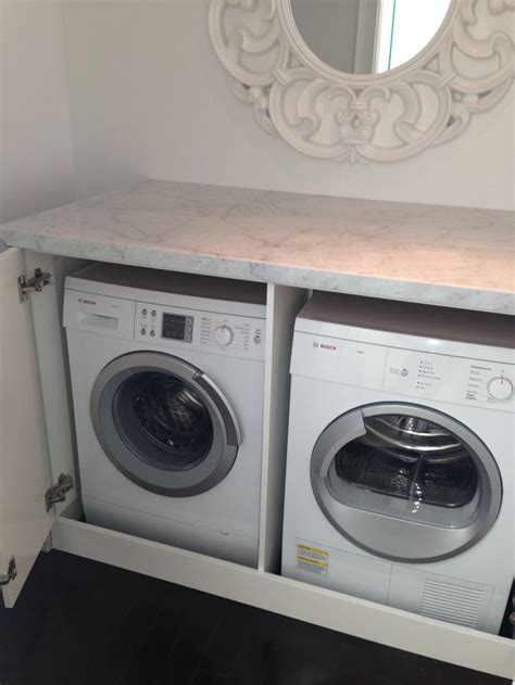 Stacked washer and dryer hidden behind a black barn door on rails in a cottage basement boasting green cabinets and light oak wood floors. Folding Doors: Folding Doors To Hide Washer And Dryer