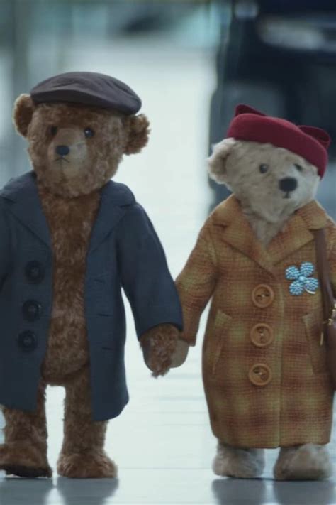 Two Teddy Bears Dressed In Coats And Hats Are Walking Down The Street
