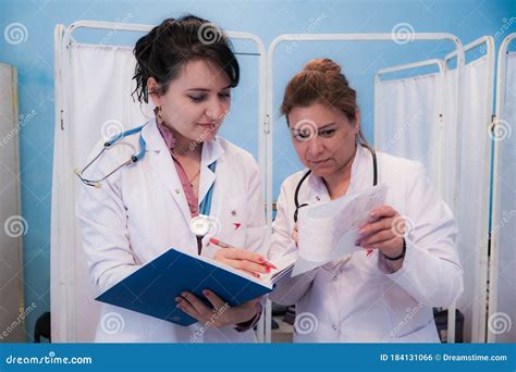 Two Women Doctors Look At Patient Testslooking Through Some Patients