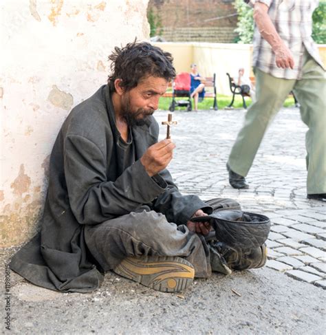 Homeless Dirty Man With Cross On The Street Of The City Stock Photo
