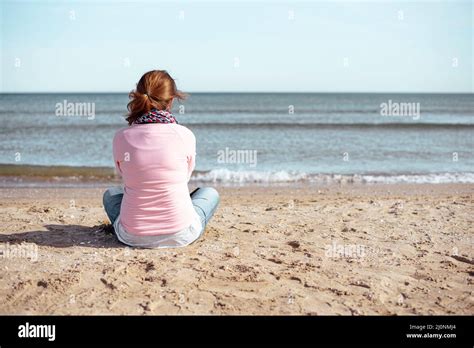 Woman Sitting On The Beach Looking At The Sea Stock Photo Alamy