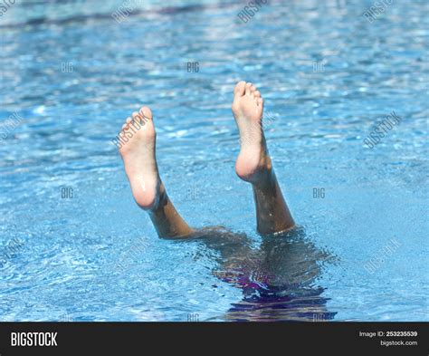 Foot Of A Girl Diving Into The Water Sticking Out Of Pool Image