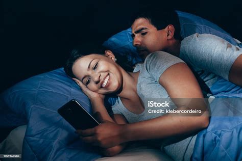 Jealous Husband Watching His Wife Mobile Phone On The Bed At Home Stock