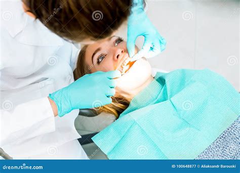 Dentista Fêmea Que Verifica Acima Dos Dentes Pacientes Com As Cintas No