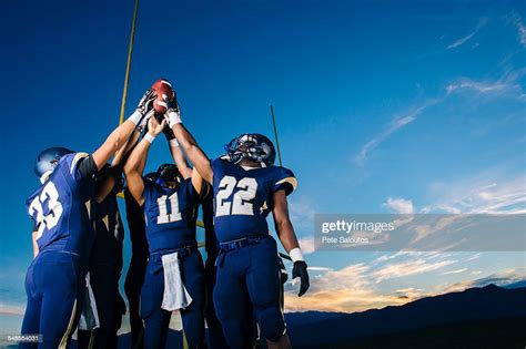 Teenage And Young Male American Football Team Celebrating And Holding