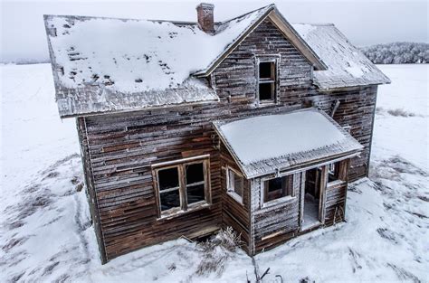 An Old Wooden House With Snow On The Roof And Windows Is Standing In A