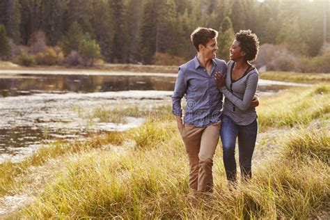 Mixed Race Couple Embracing Walking Near A Rural Lake Stock Image