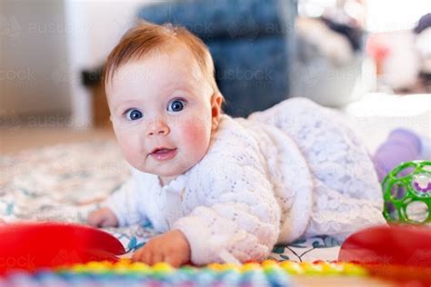 Image Of Happy Baby Girl With Bright Blue Eyes Playing With Colourful