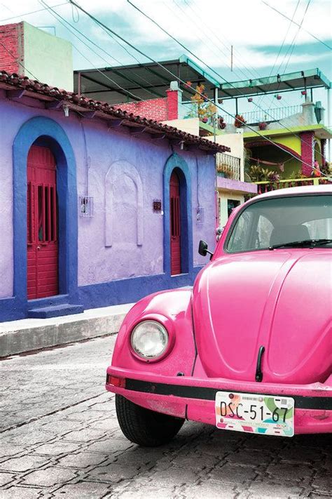 A Yellow Vw Bug Parked In Front Of Pink Buildings On A Cobblestone Street