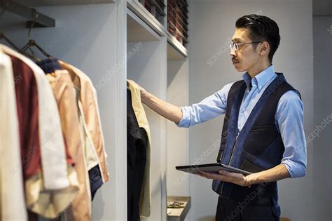 Japanese Salesman In Clothing Store Looking At Clothes Stock Image