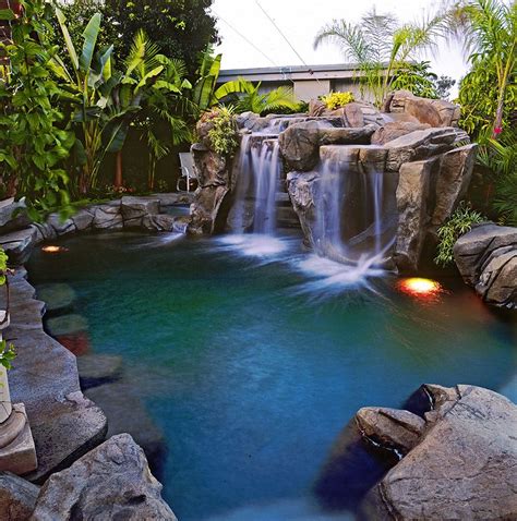 An Outdoor Pool With Waterfall And Rocks In The Middle Surrounded By