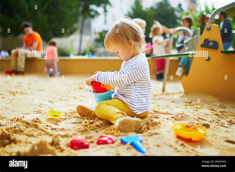 Adorable Little Girl On Playground In Sandpit Toddler Playing With