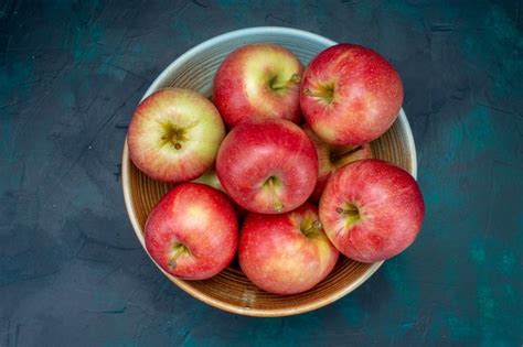 Vista de cima maçãs vermelhas frescas suculentas e maduras no prato sobre a mesa azul escuro