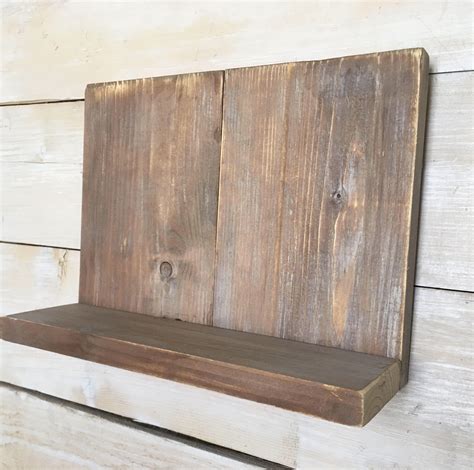 A Wooden Shelf Mounted To The Side Of A White Wood Planked Wall With Two Holes In It