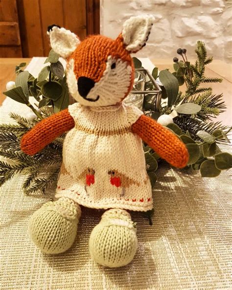 A Knitted Fox Doll Sitting On Top Of A Table Next To Greenery And