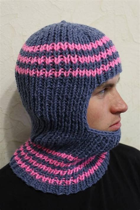 A Man Wearing A Blue And Pink Knitted Hat With A Hood On His Head