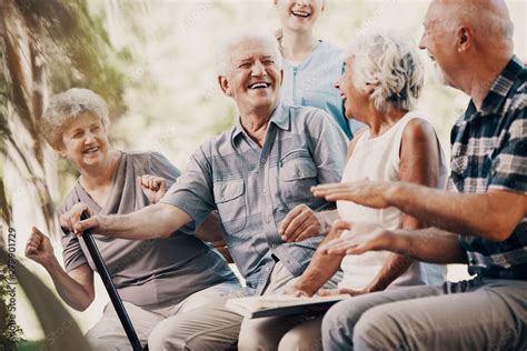 happy elderly man with walking stick and smiling senior people relaxing in the garden stock