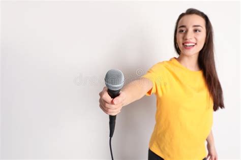Young Woman Holding Microphone And Smiling On Color Background Stock