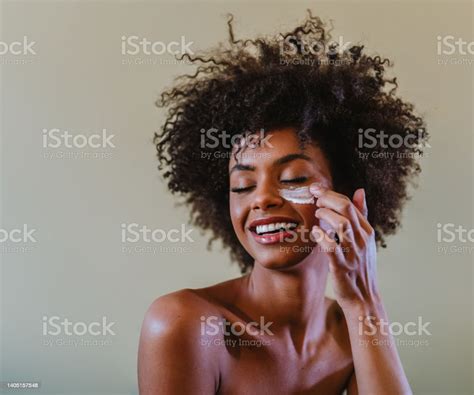 Close Up Portrait Of Latina Woman Applying Facial Cream To Her Face