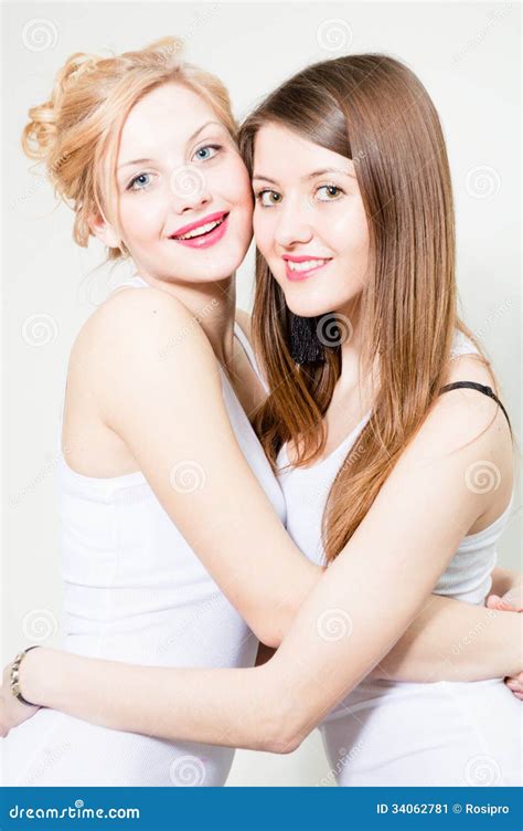 Two Happy Smiling Women Friends Embracing And Smiling In Studio Stock
