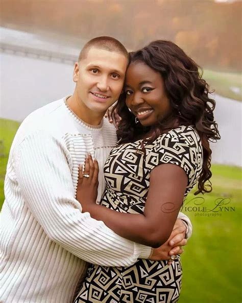 a man and woman hugging each other in front of a lake