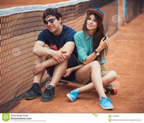Couple Sitting On A Skateboard On The Tennis Court Stock Image Image