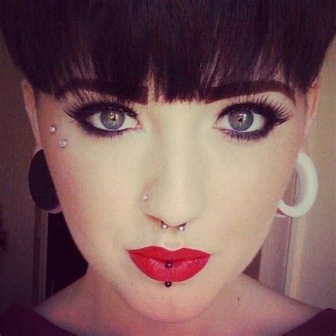 A Woman With Black Hair And Piercings On Her Nose Is Wearing Red