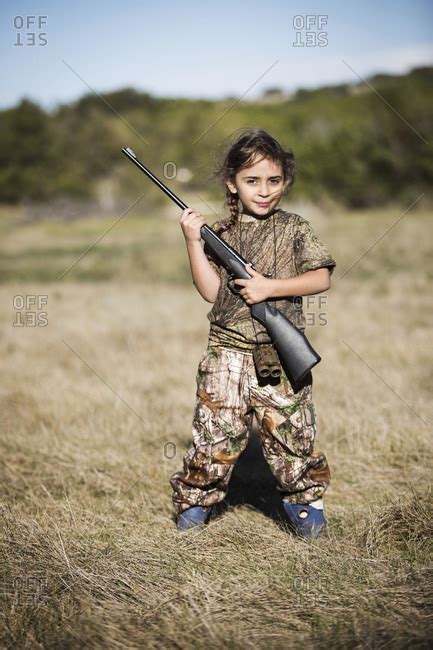 A Little Girl Stands In A Field Holding A Rifle Stock Photo Offset