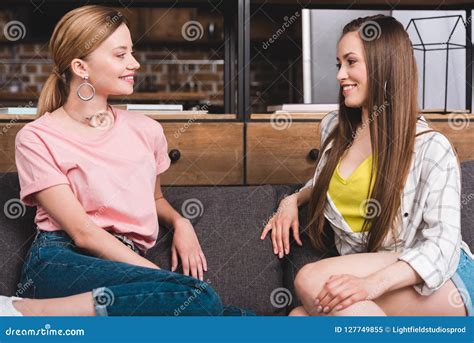Smiling Young Female Friends Talking To Each Other While Sitting On Sofa Stock Image Image Of