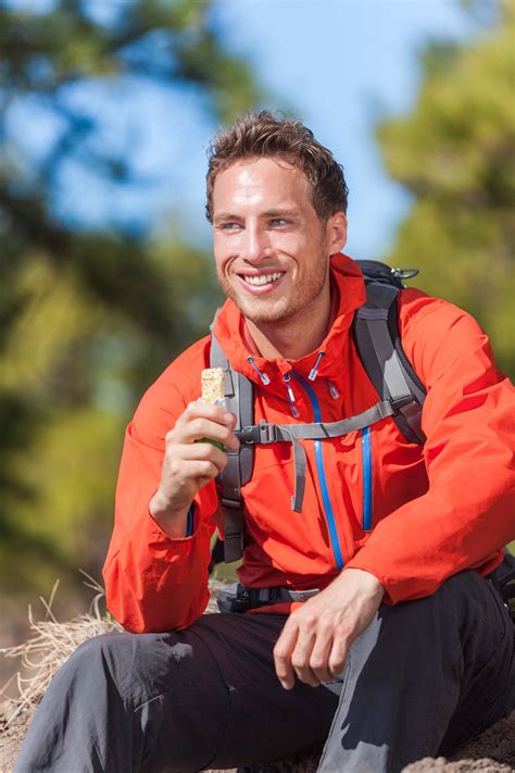 Nourish your body with all the flavor and feed your soul. Hiker man healthy outdoor lifestyle eating muesli bar ...