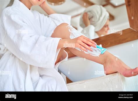 Closeup Image Of Girl Shaving Her Legs In Bath In Apartment Stock Photo