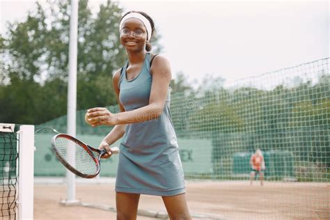 Black American Female Tennis Player Playing On The Court Outdoors Stock