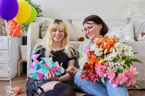 Mom Congratulating Daughter With Bouquet Of Flowers And Surprise T