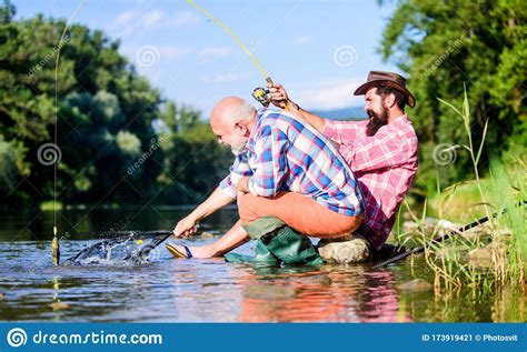Men Sit At Riverside With Fishing Equipment Poaching Crime And Fishing