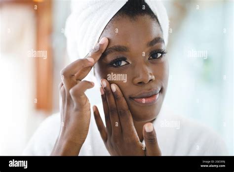 Portrait Of Smiling African American Woman In Bathroom Touching Her Face Before Beauty Treatment
