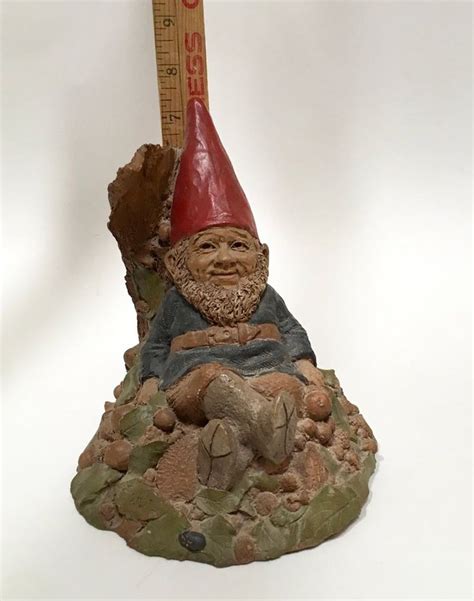 A Gnome Figurine Sitting On Top Of A Rock Next To A Ruler