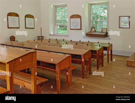 A Vintage One Room Schoolhouse With Wooden Desks On The Grounds Of The