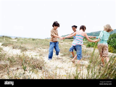 Children Playing Ring Around The Rosy On Grassy Beach Stock Photo Alamy