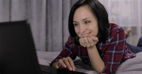 Young Brunette Woman Lying On The Bed Chatting Working On The Laptop
