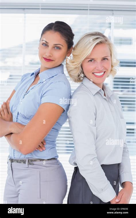 Attractive Businesswomen With Arms Crossed Standing Back To Back Stock