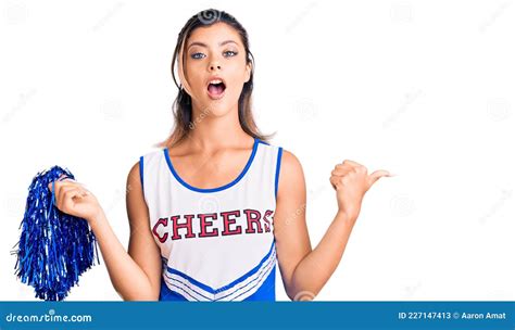 Young Beautiful Woman Wearing Cheerleader Uniform Surprised Pointing With Hand Finger To The