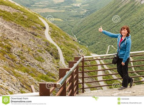 Tourist woman looking at mountains, taking picture with camera from trollstigen viewing point, norway. Tourist Woman On Trollstigen Viewpoint In Norway Stock ...