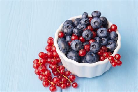 Assorted Berries In White Bowl On Wood Blueberry And Red Currant On