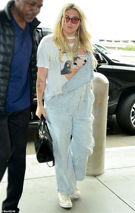 Kesha Unbuttons Her Overalls To Reveal Slashed Tee Shirt And Bare Her