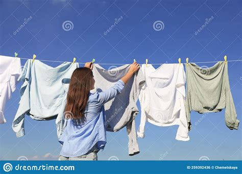 Woman Hanging Clothes With Clothespins On Washing Line For Drying