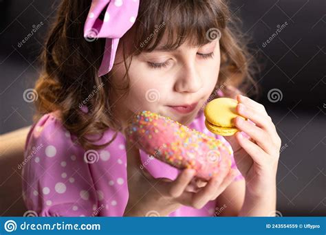 Close Up Of Attractive School Girl On Home Background Licks Her Lips Sniffing Donut And Yellow