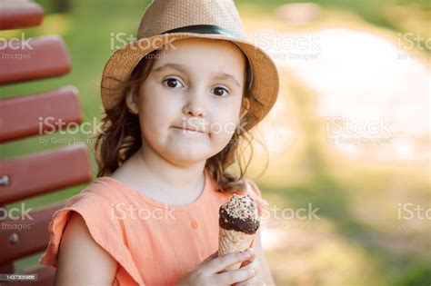 아이스크림 콘을 먹는 모자에 귀여운 어린 소녀 공원 벤치에 앉아서 웃고있는 아이 여름 개념 거품 내기에 대한 스톡 사진 및 기타 이미지 istock